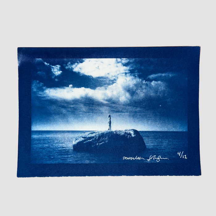 Cyanotype depicting ionnalee standing on a rock in a lake, by John Strandh